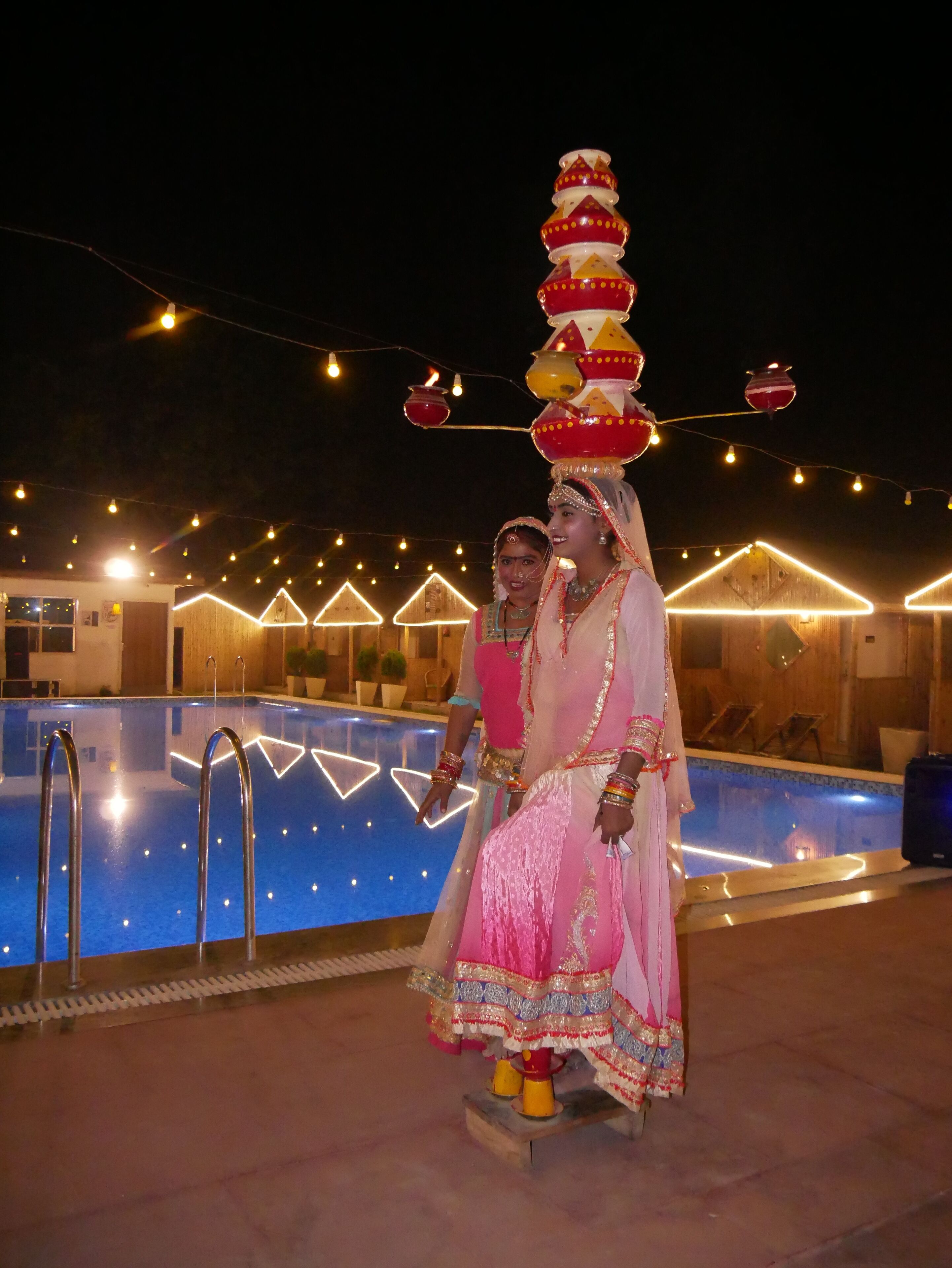 A pool area with a decorative structure and string lights.