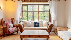 A cozy room with a wooden bench, a sofa, and a chair with a plaid blanket. - The Old Rectory (Tring)