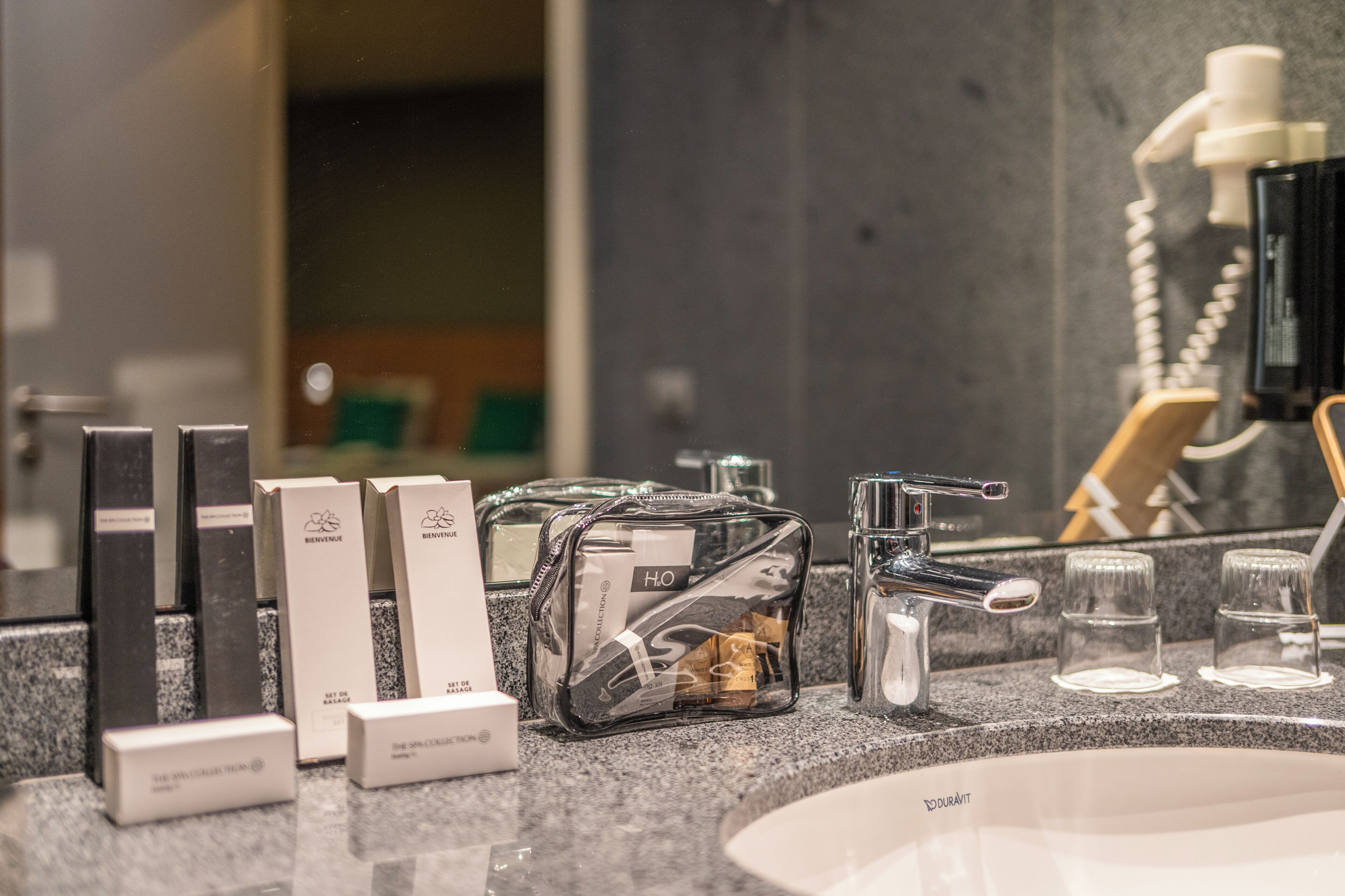 A bathroom counter with toiletries, a mirror, and a sink.