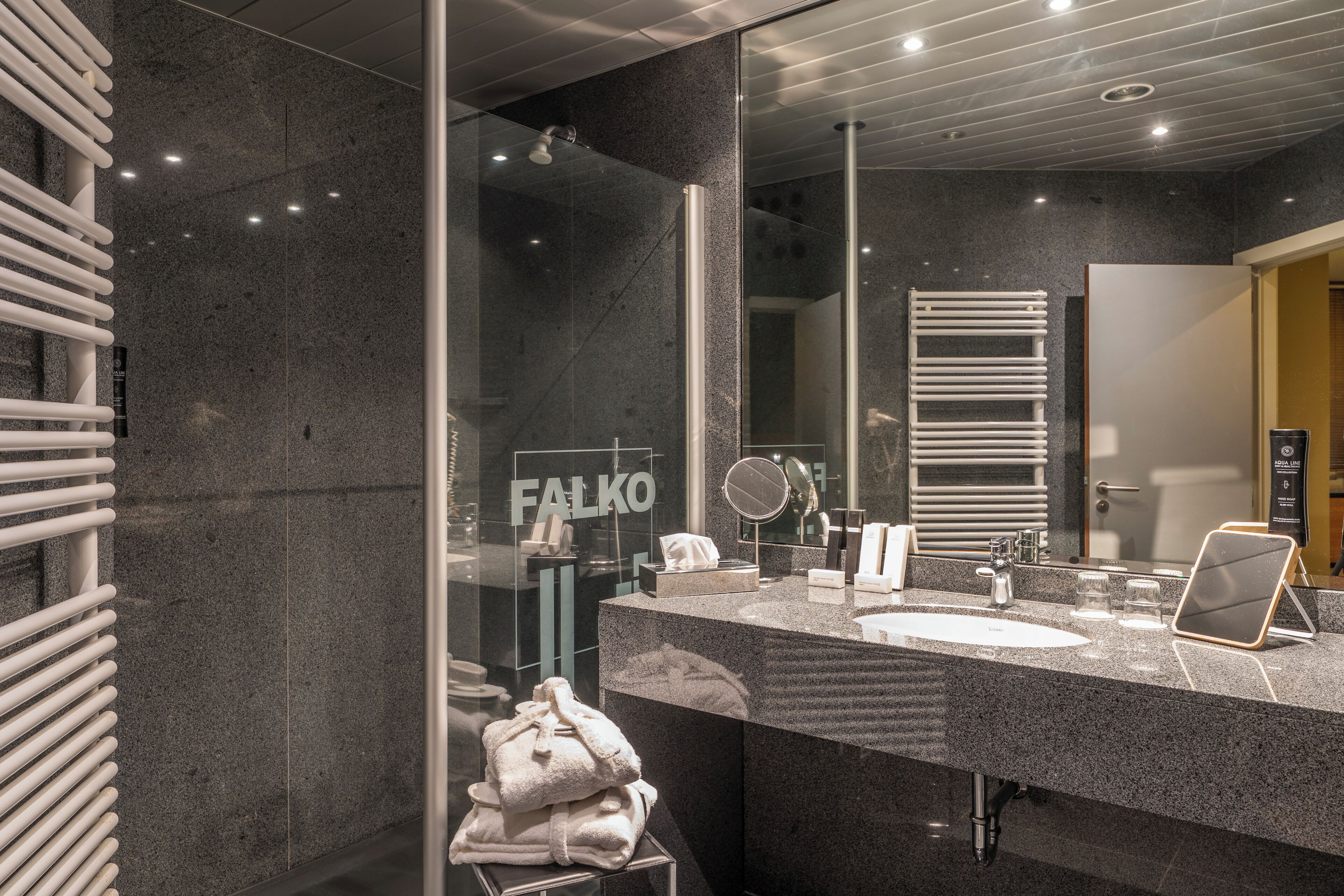 A modern bathroom with a large mirror, a sink, and a towel rack.