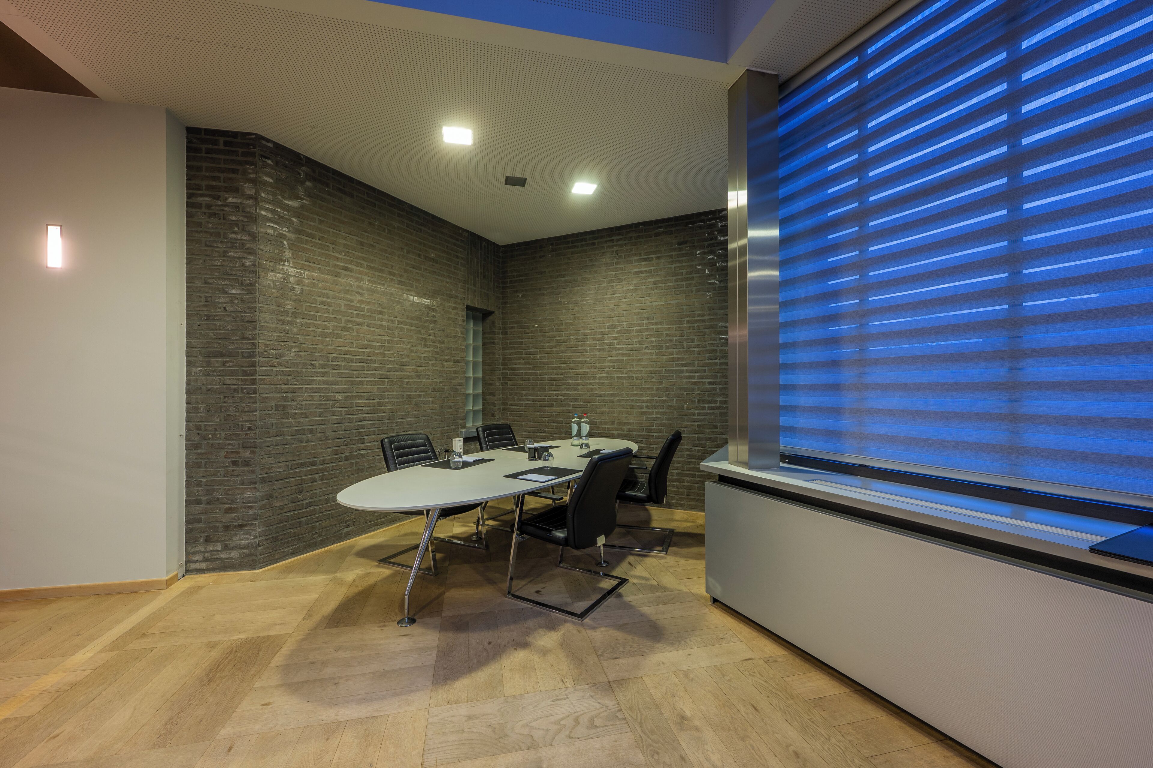 A conference room with a white table, black chairs, and a brick wall.