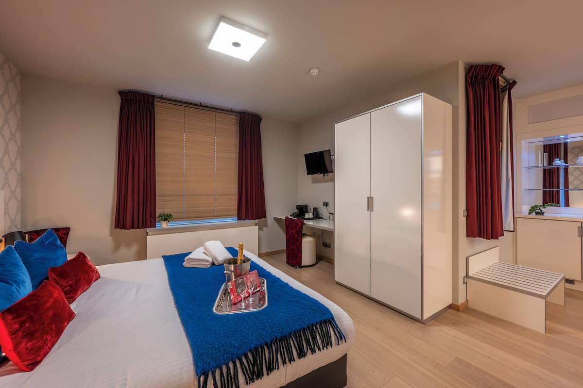 Une chambre d’hôtel comprenant un lit, un bureau, une armoire et un petit coin salon.