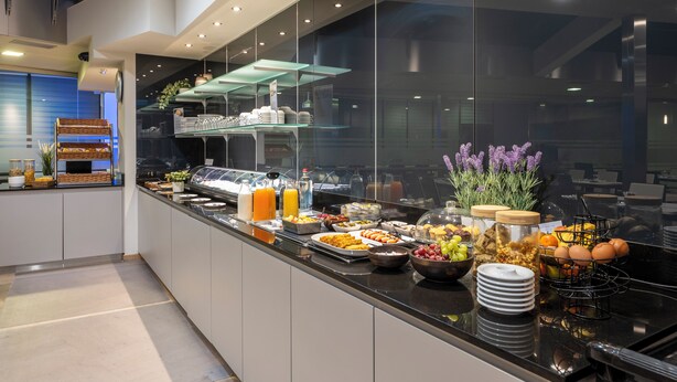A buffet with various food items and drinks, a glass display case, and a modern interior design. - Falko Hotel (Meise)