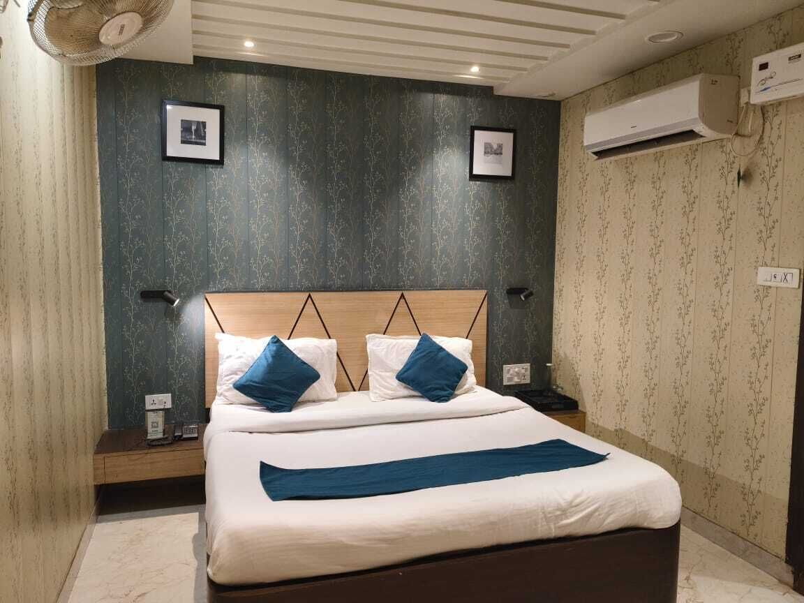 Un letto rifatto con cura, con una testiera in legno, due comodini con lampade e un condizionatore d'aria a parete.