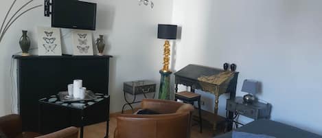 Een slaapkamer met een bed, een bureau, een stoel, een televisie, een kroonluchter en een klein beeldje.