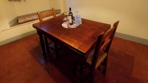 Un comedor con una mesa y sillas de madera, una lámpara y una ventana con cortinas.