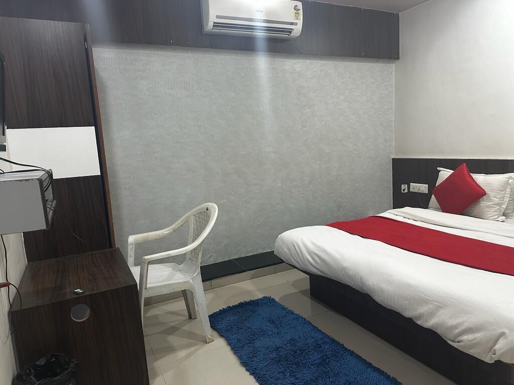 Een hotelkamer met een bed, een bureau, een stoel en een airconditioning.