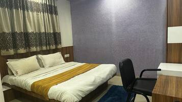 A bedroom with a bed, a desk, a chair, and a wardrobe.