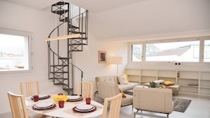 A modern living room with a spiral staircase, a dining area with a table set for four, and a sofa with cushions. - Luxury Nassa Penthouse with Private Terrace in Lugano (Lugano)