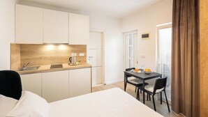 A compact hotel room with a kitchenette, a dining area, and a bed. - Apartments & Rooms Buble - Studio with terrace (Trogir)