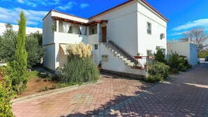 A two-story building with a red-tiled roof, a staircase leading to the upper floor, and a paved driveway. - Apartments & Rooms Buble - Studio with terrace (Trogir)