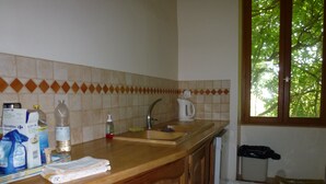 Une cuisine avec un plan de travail en bois, un évier et une fenêtre donnant sur des arbres.