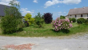 Un paysage rural comprenant une maison, une zone herbeuse et une route asphaltée.