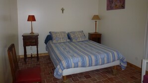 Une chambre à coucher comprenant un lit, deux tables de chevet avec des lampes, une chaise et une œuvre d’art accrochée au mur.