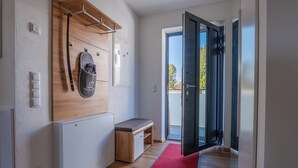 A hallway with a wooden bench, a red rug, and a door leading to a balcony. - Dießen, Ammersee-Nest, new, bright, 90sqm, 2 bedrooms, balcony, parking spaces, premium (Dießen am Ammersee)