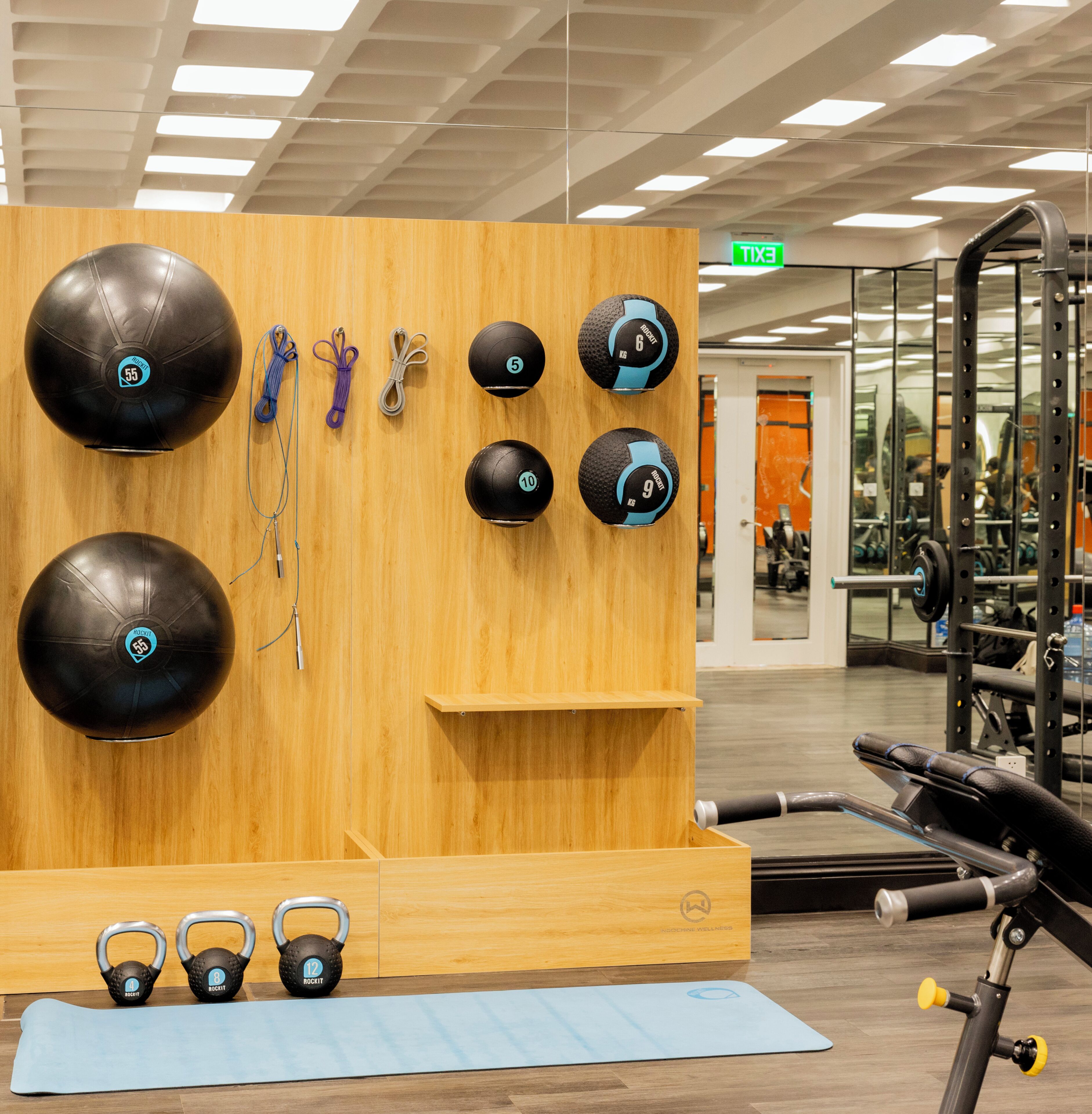 A gym with exercise equipment, including kettlebells, medicine balls, and a yoga mat.