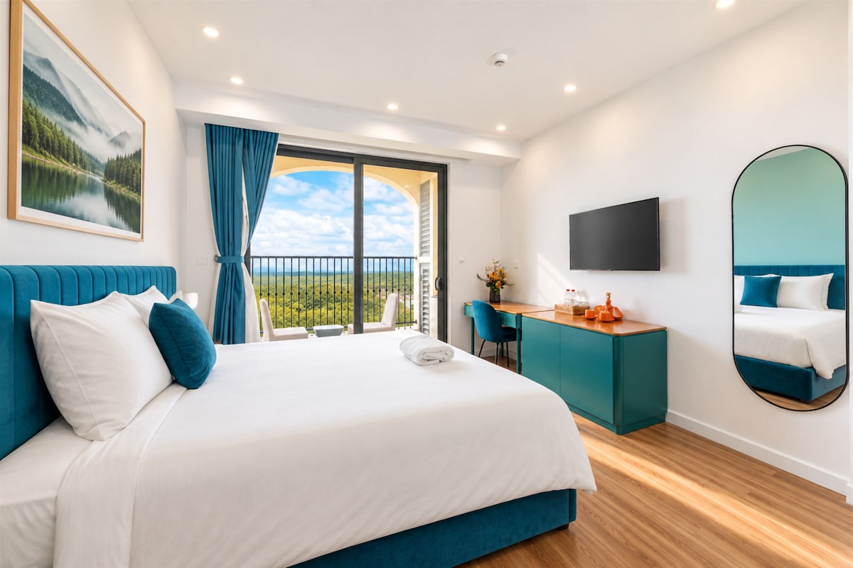 Een moderne hotelkamer met een groot bed, een bureau, een televisie en een balkon met een mooi uitzicht.