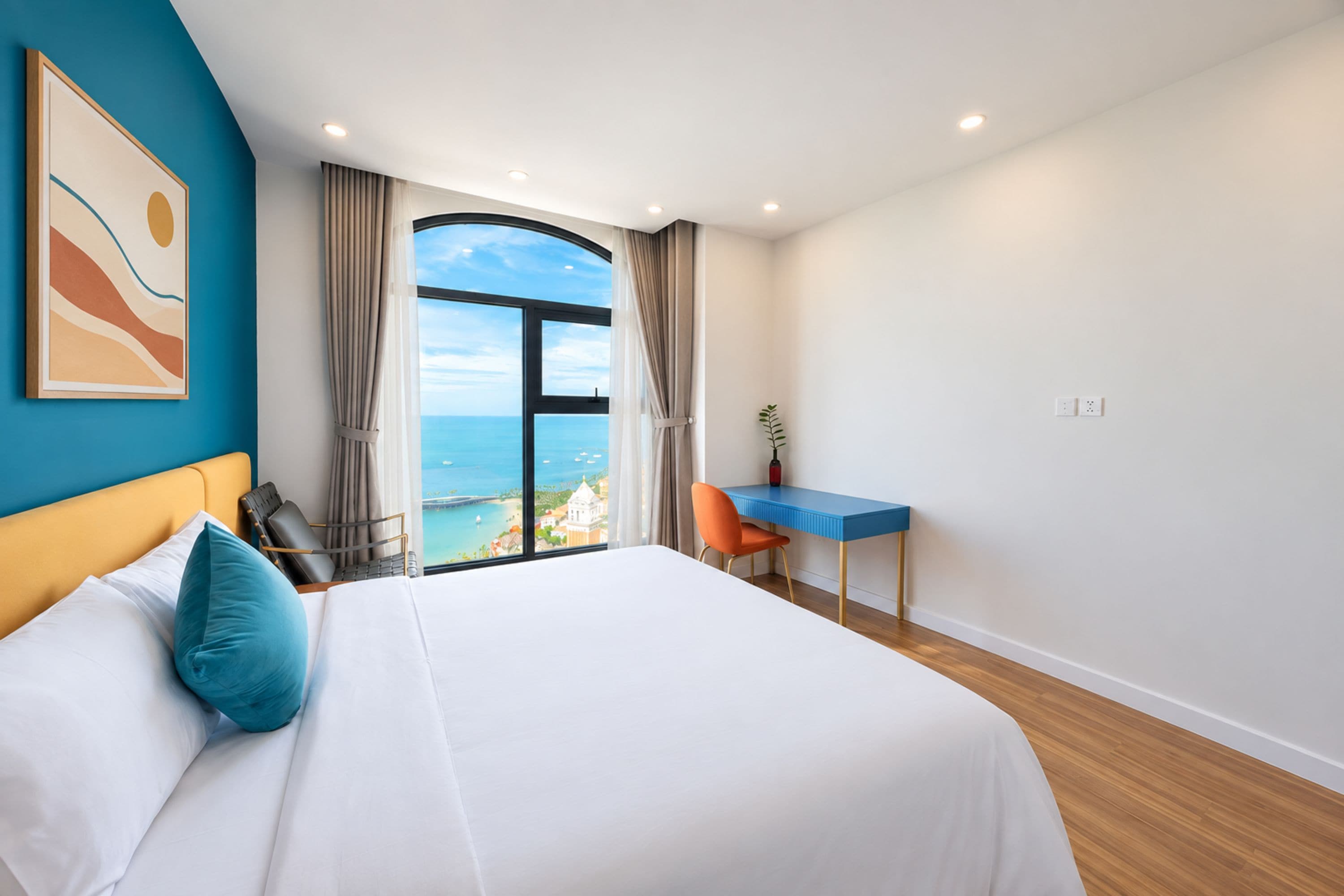 Habitación de hotel con una cama grande, un escritorio y vistas al mar.