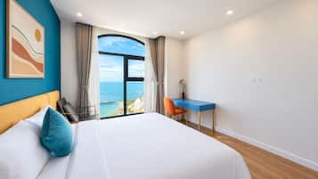 Habitación de hotel con una cama grande, un escritorio y vistas al mar.