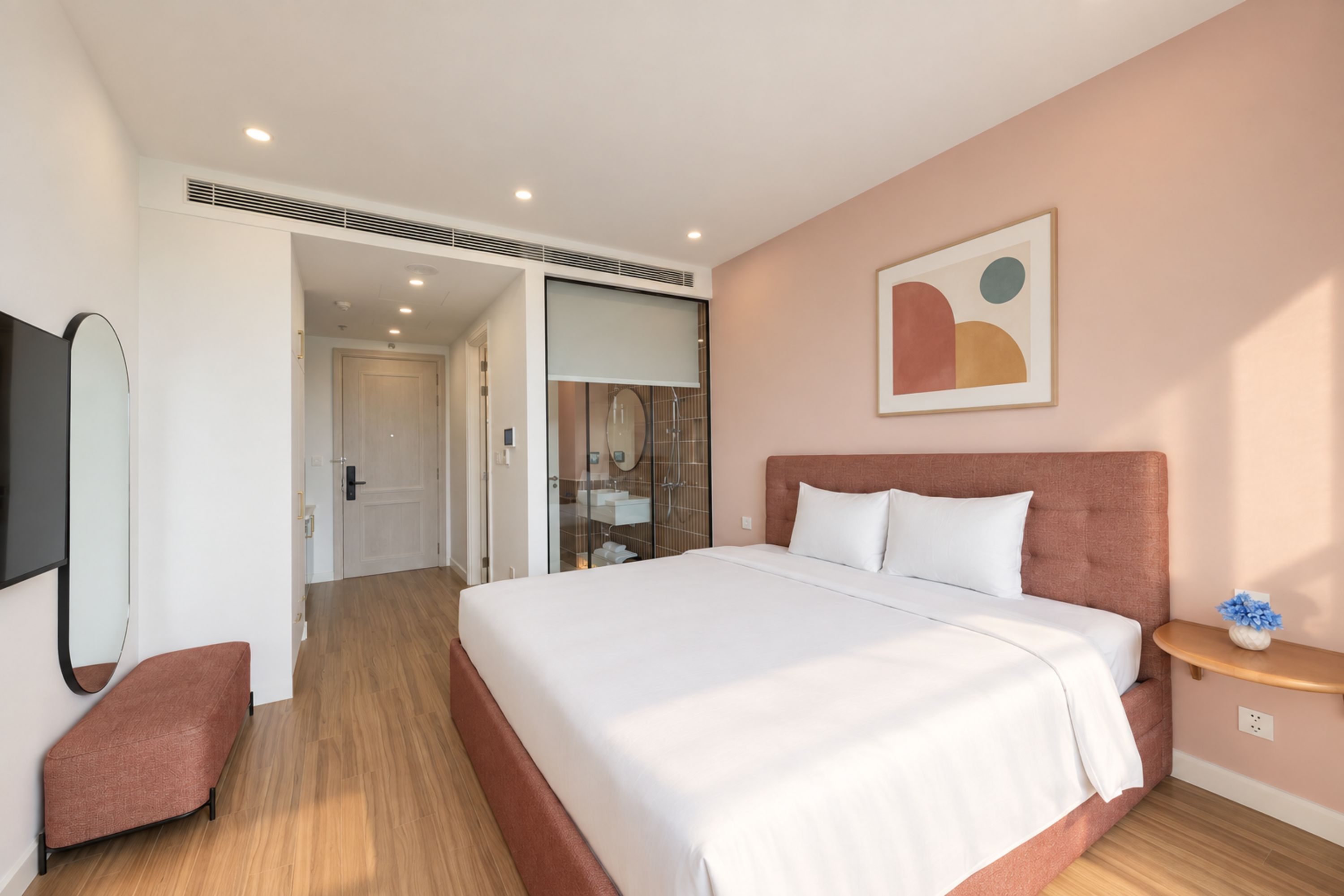 Een moderne slaapkamer met een groot bed, een nachtkastje, een spiegel en een wanddecoratie.