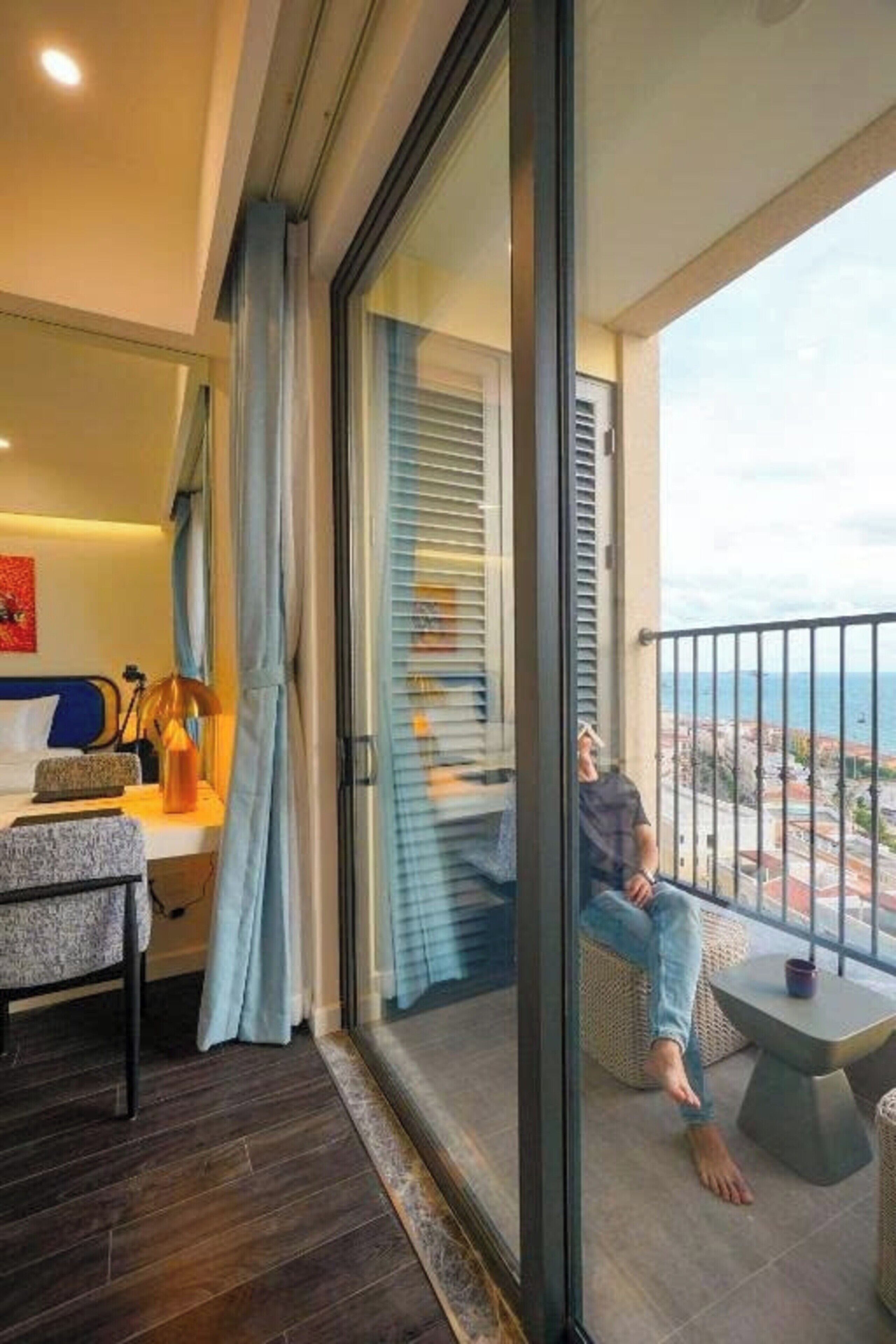 A modern bedroom with a large sliding glass door leading to a balcony.