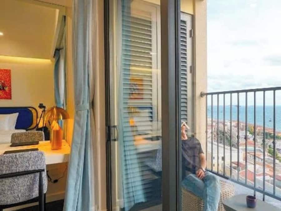 Un dormitorio moderno con un amplio ventanal corredera que da a un balcón.