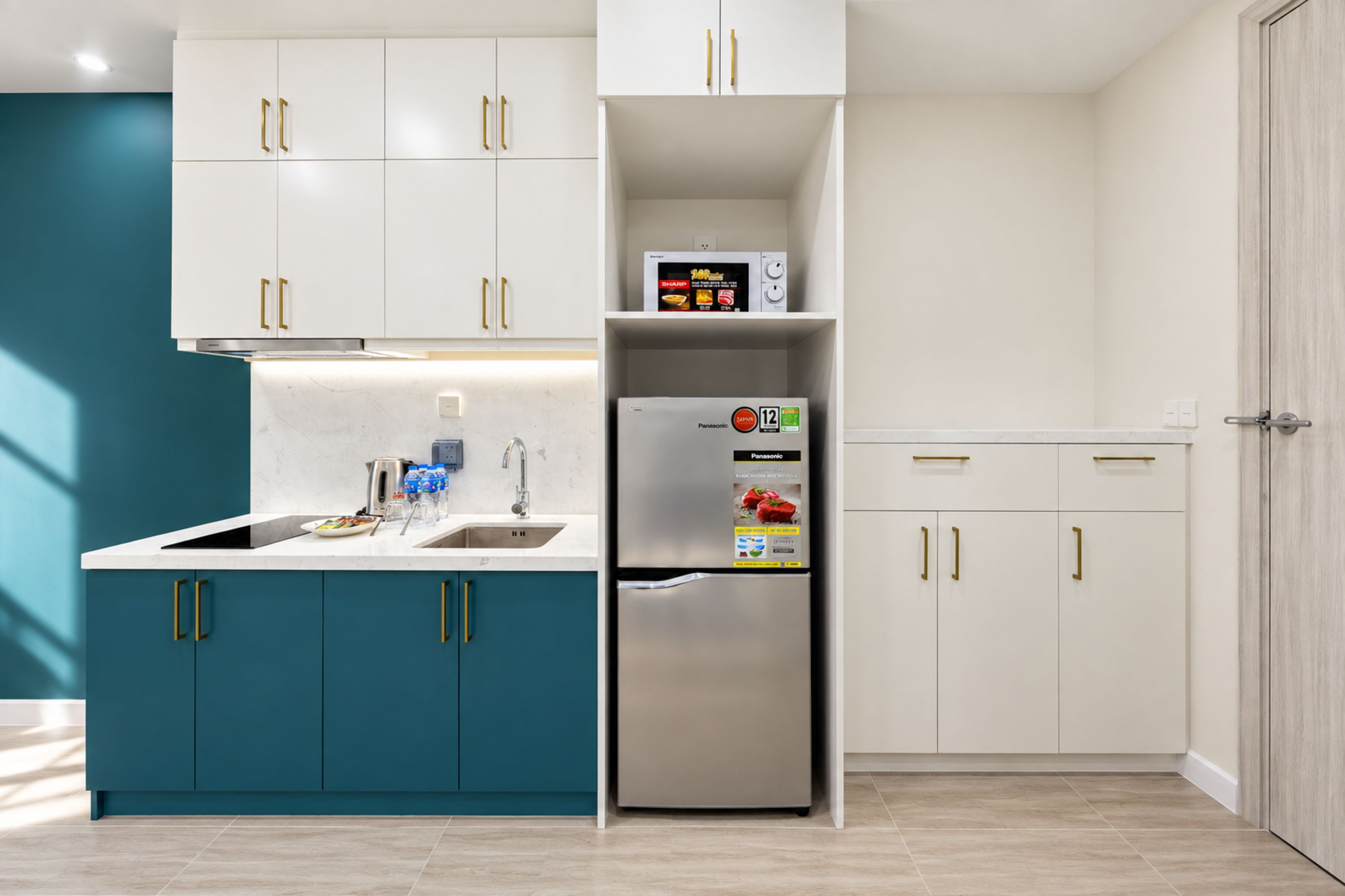 Une cuisine moderne avec des armoires de couleur turquoise, un réfrigérateur en acier inoxydable et des armoires blanches en partie supérieure.