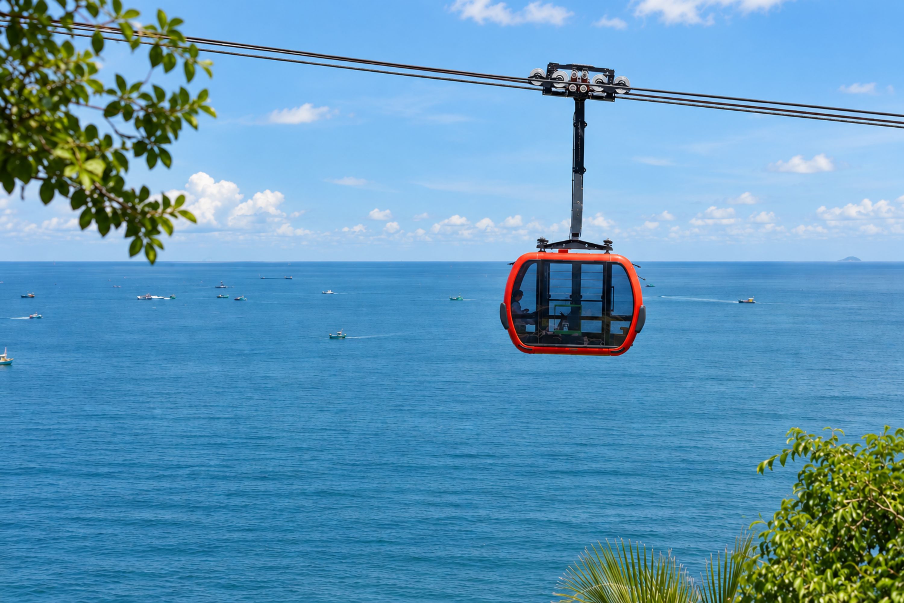 A cable car suspended over a body of water with boats visible below.