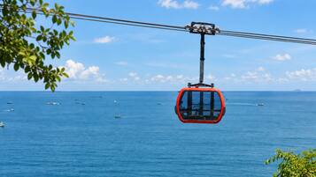 Un teleférico suspendido sobre una masa de agua, con embarcaciones visibles abajo.