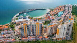 An aerial view of a coastal residential area with high-rise buildings, a marina, and a bridge. - Luna Sol - Sunset & Firework Signature (Phu Quoc)