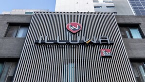 A building with a modern facade featuring vertical slats and a prominent logo. - ILLUWA-M (Seoul)