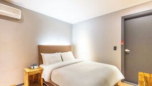 A hotel room with a bed, bedside table, and a door. - ILLUWA-M (Seoul)