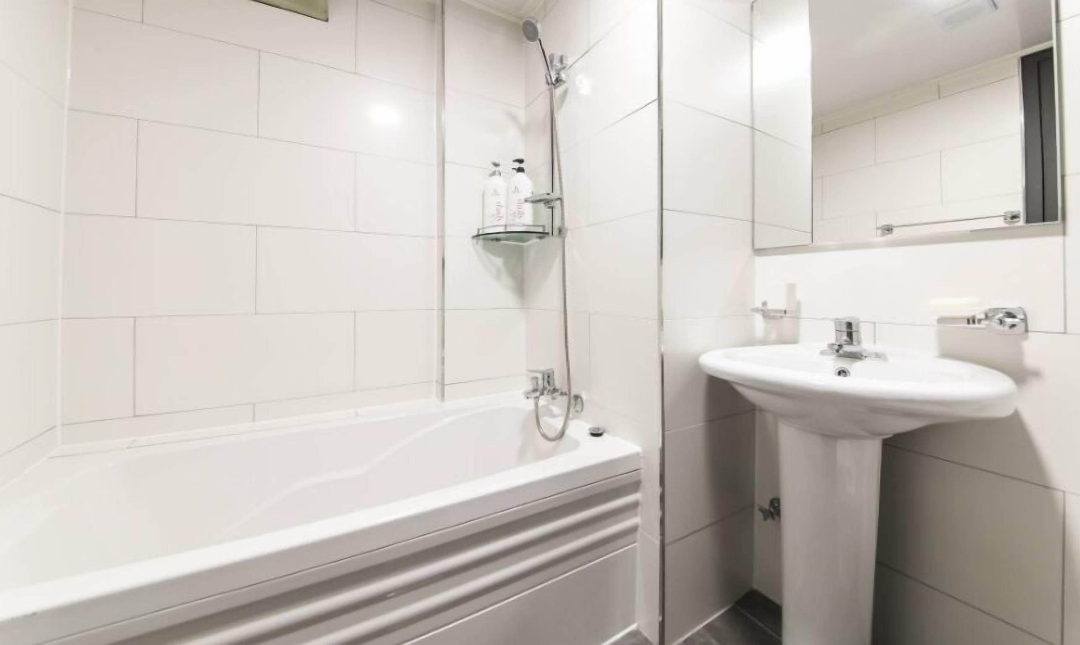A modern bathroom with a white bathtub, a sink, and a shower.