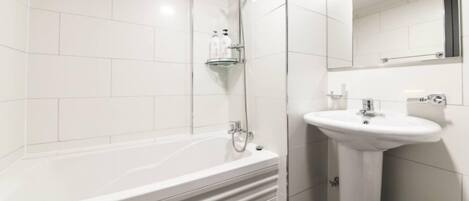 A modern bathroom with a white bathtub, a sink, and a shower.