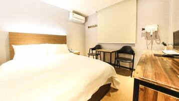 Une chambre d’hôtel avec un grand lit, un bureau avec une chaise, un appareil de climatisation et un téléphone.