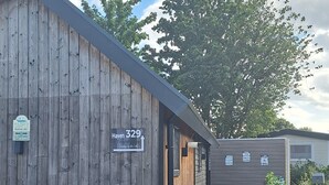 A wooden building with a sign reading "Haven 329 Tiny House." - Tinyhouse / chalet at the Rhederlaagse Meren vacation park in NL-Lathum by the lake (Lathum)