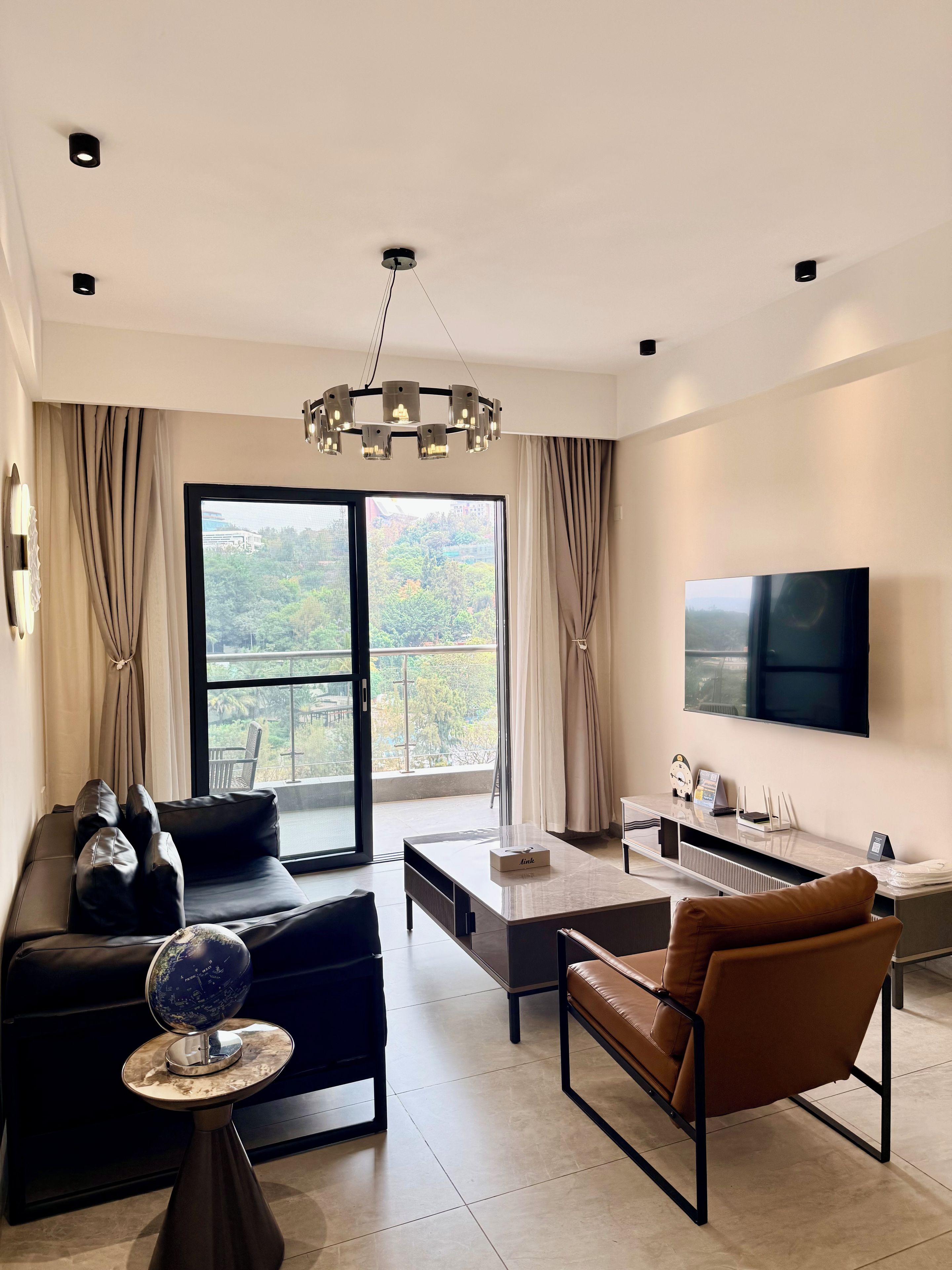 Una sala de estar moderna con sofá, sillón, mesa de centro y un televisor de pantalla plana montado en la pared.