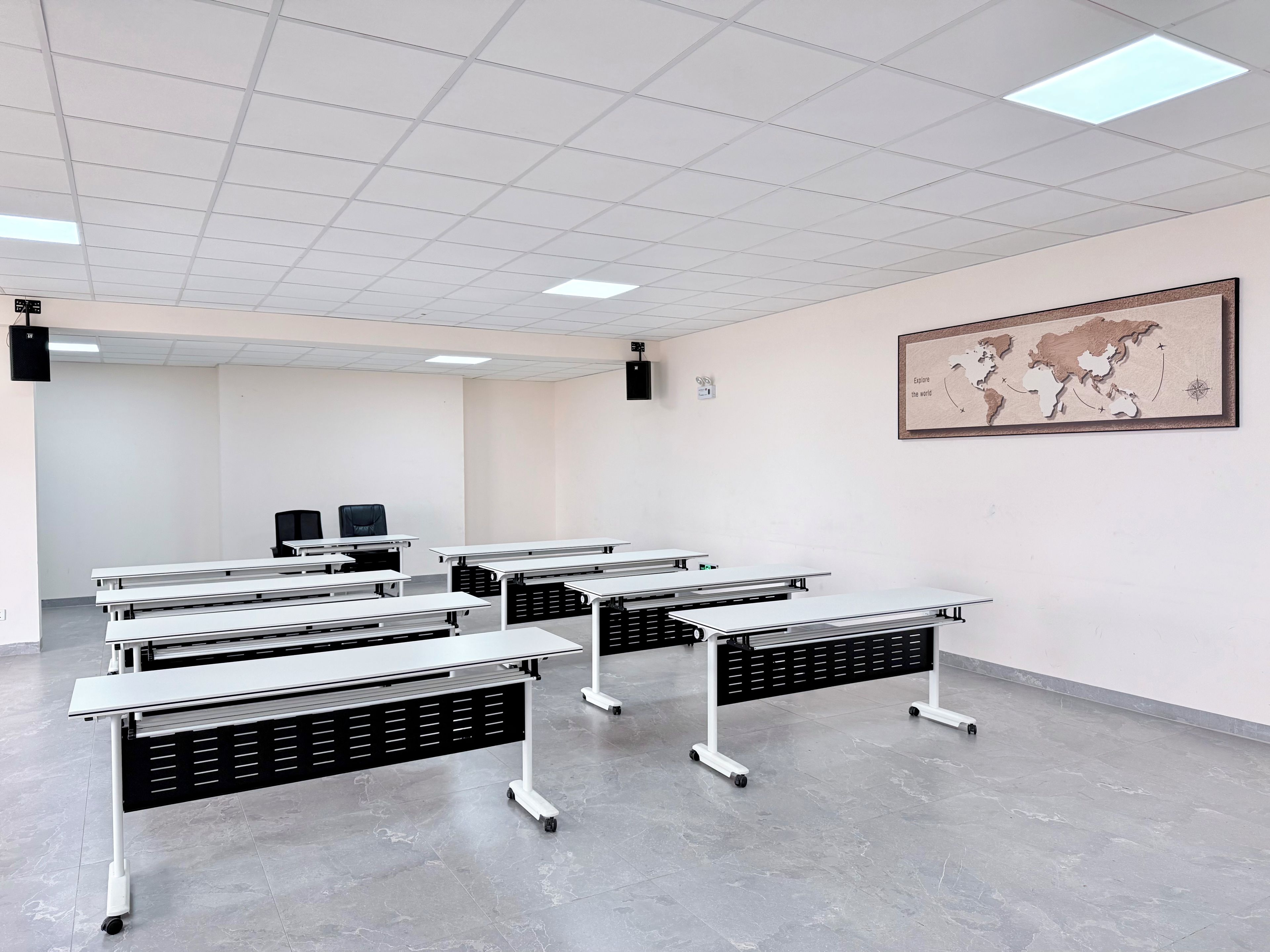 Un aula con varias mesas, un proyector y un mapa mundial en la pared.