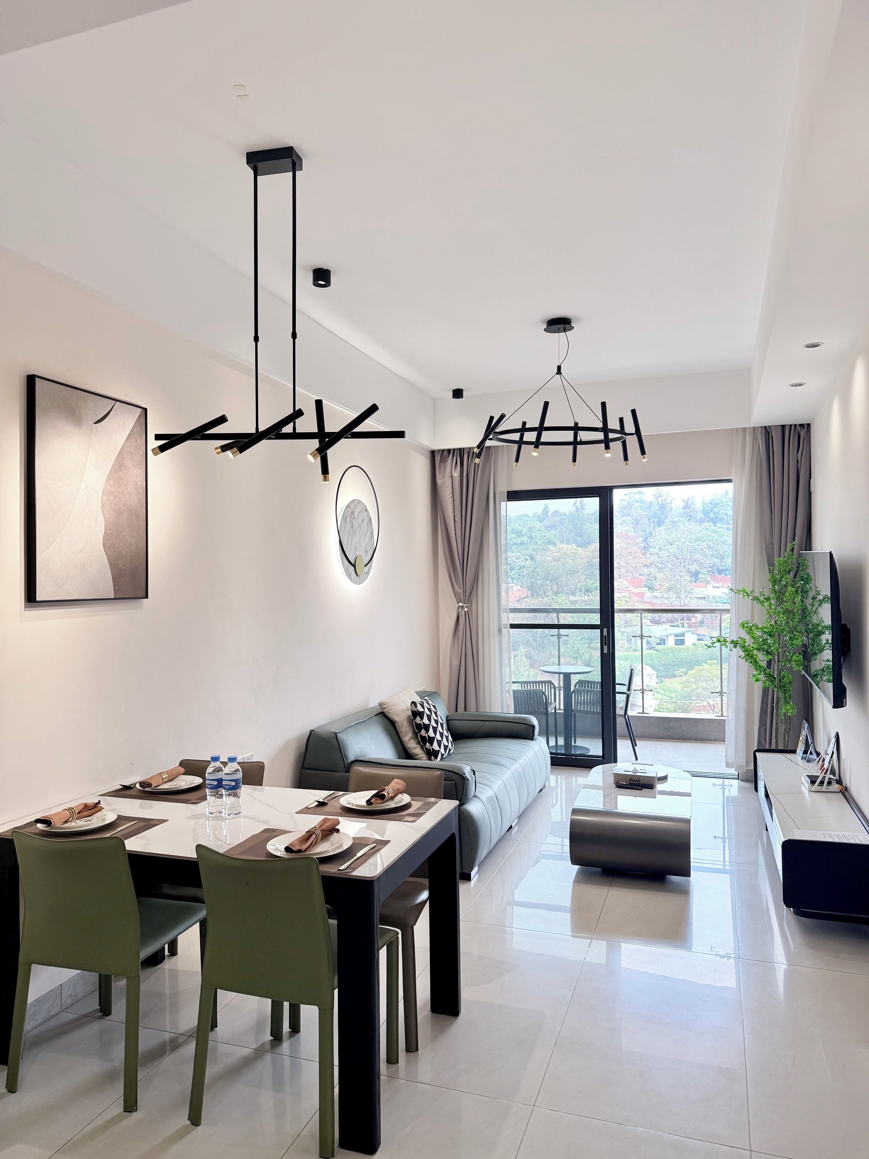 A modern living room with a dining area, a sofa, a TV, and a balcony with a view.