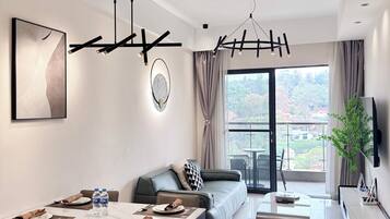 A modern living room with a dining area, a sofa, a TV, and a balcony with a view.