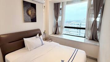 Habitación de hotel con cama, mesita de noche, ventana con cortinas y aire acondicionado instalado en la pared.