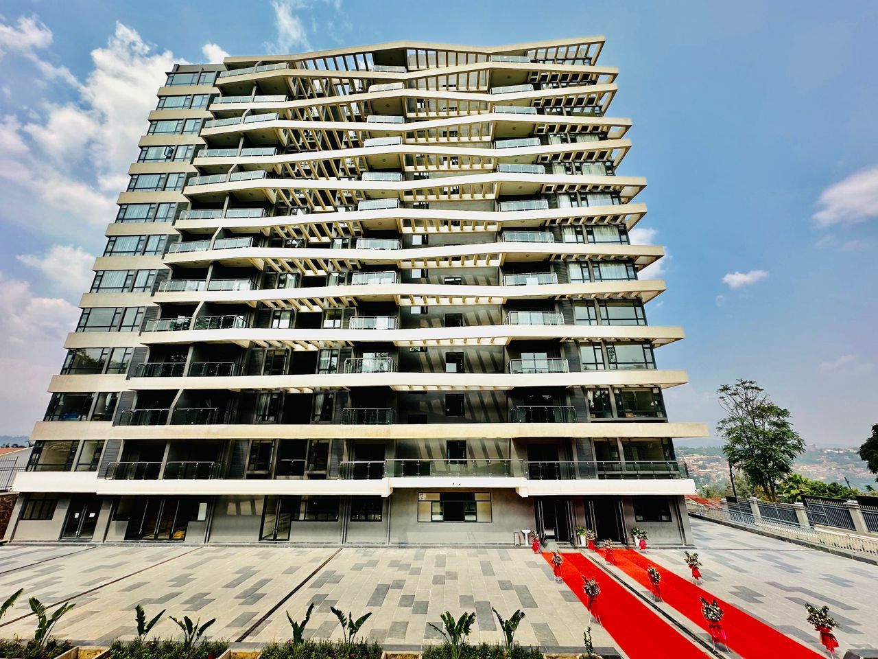 Un immeuble à plusieurs étages, doté de balcons et d’un tapis rouge menant à l’entrée.