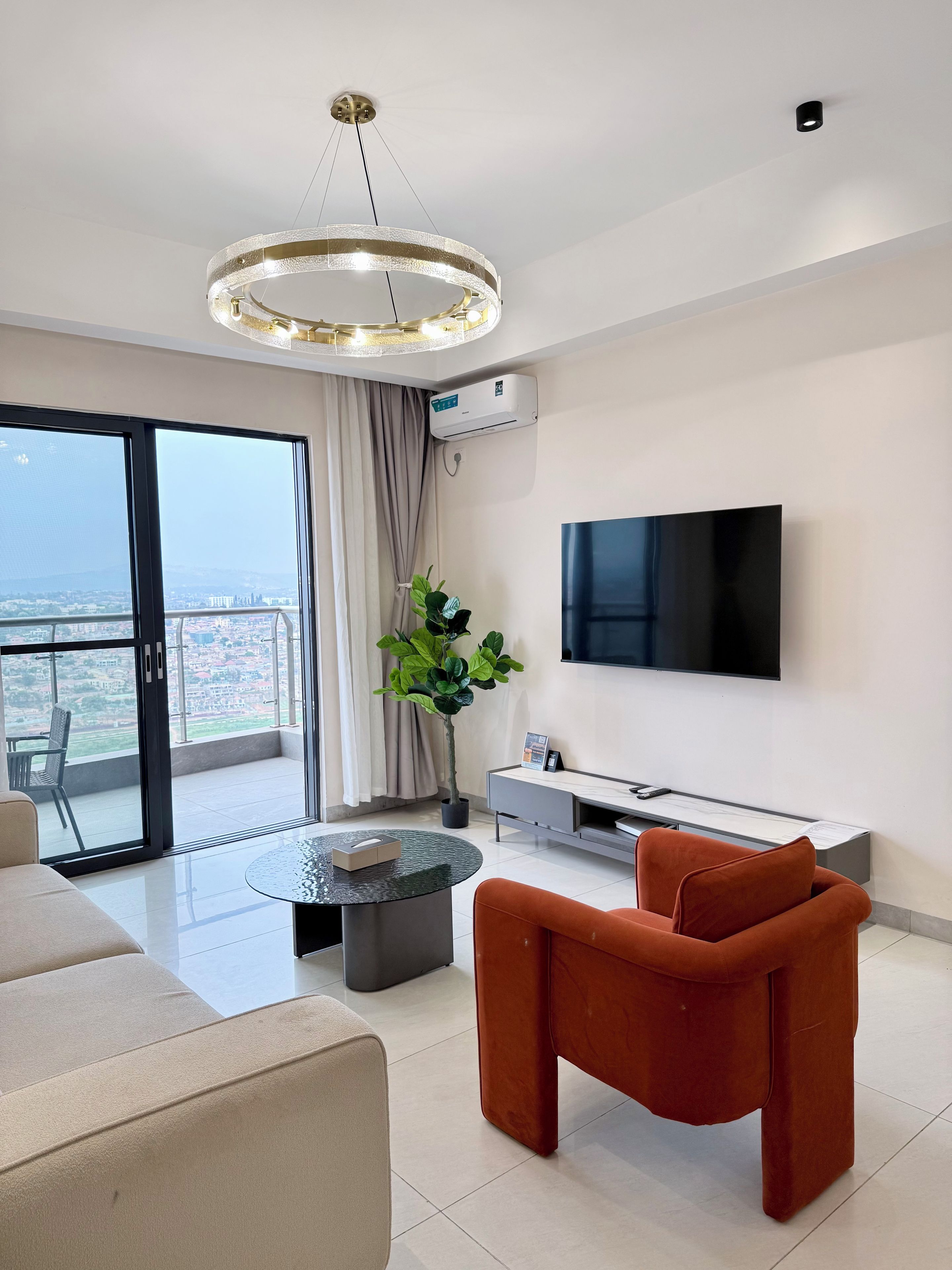 A modern living room with a sofa, a coffee table, a TV, and a potted plant.