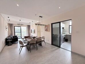 A modern living space with a dining area, a sofa, and a kitchen. - Greenland Apartment by Link (Kigali)