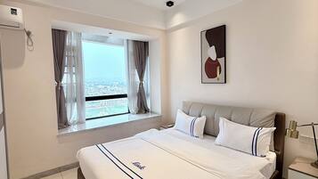 Une chambre d’hôtel moderne avec un grand lit, une fenêtre avec des rideaux, une table de chevet et une œuvre d’art accrochée au mur.