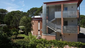 A multi-story building with a balcony on the upper floor, a staircase, and a chimney.