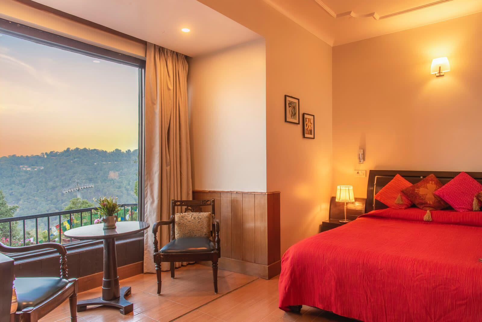 Une chambre d’hôtel avec un grand lit, une chaise, une table et une vue sur un paysage montagneux.