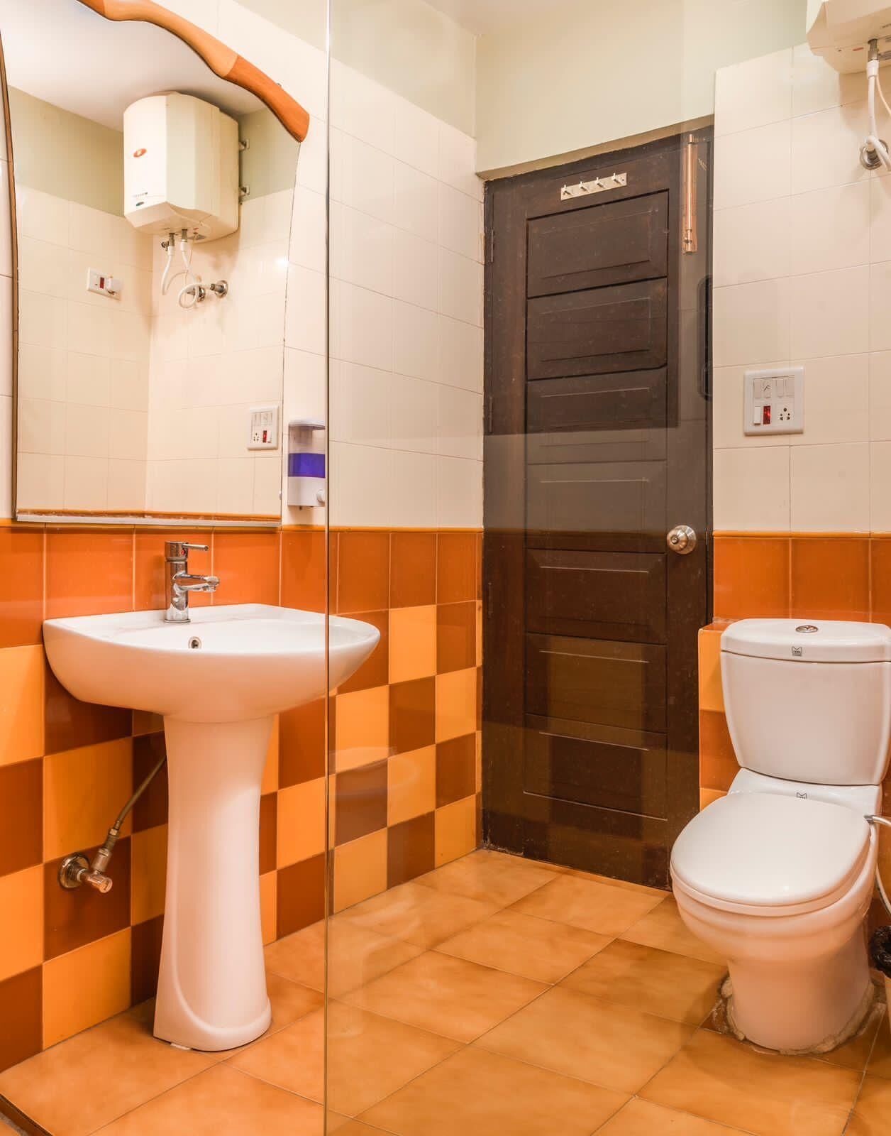 A bathroom with a white sink, a toilet, a shower, and a dark door.