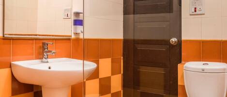 A bathroom with a white sink, a toilet, a shower, and a dark door.