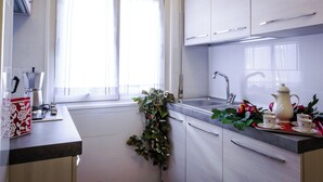 A modern kitchen with white cabinets, a stainless steel sink, and a window with sheer curtains.